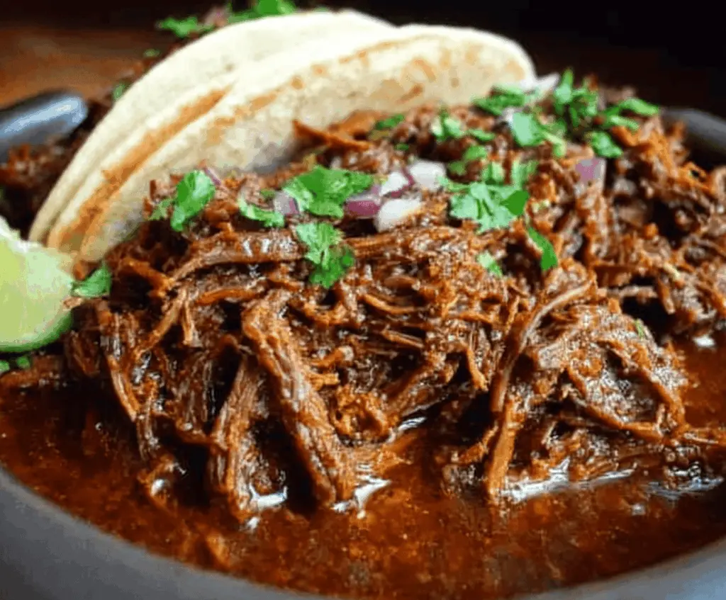 Tender and flavorful Slow Cooker Barbacoa with shredded beef, served with fresh toppings and warm tortillas, perfect for Mexican-inspired tacos.