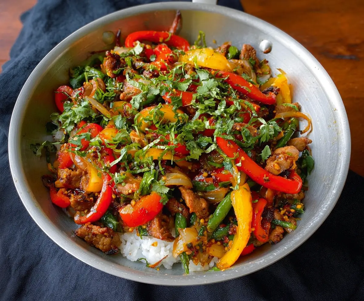 Delicious garlic pork stir fry garnished with fresh herbs on a dinner plate.